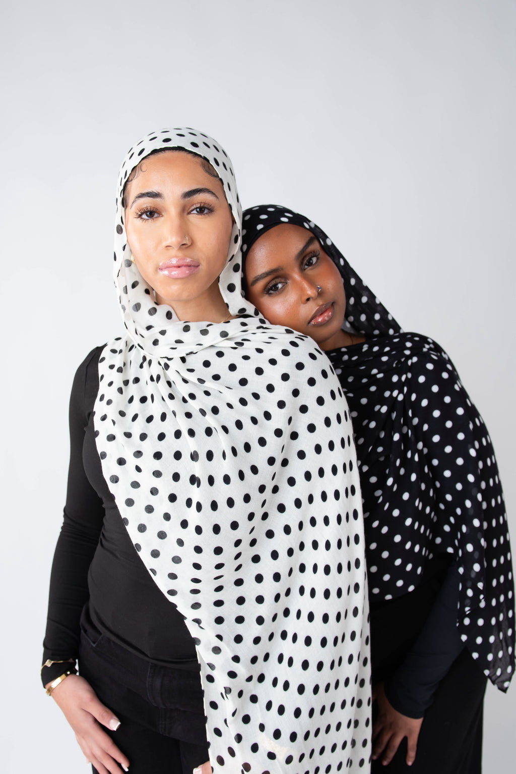 Two women wearing polka dot modal hijabs against a white background